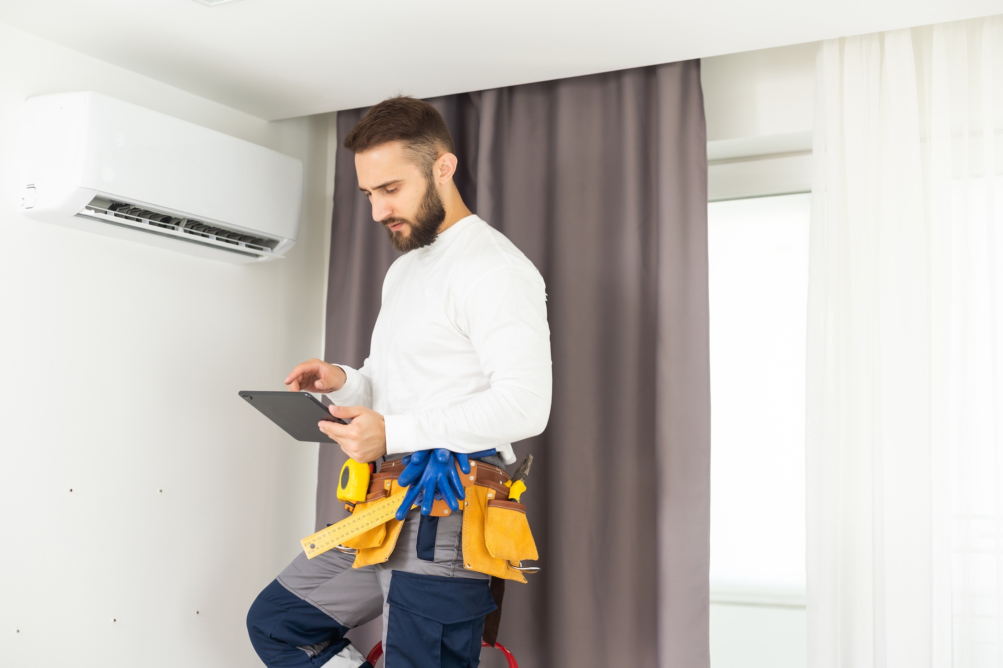 male technician service worker diagnosing for repairs air conditioner. person using tablet.