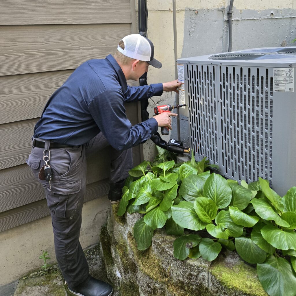 HVAC technician servicing an outdoor air conditioning unit in Everett