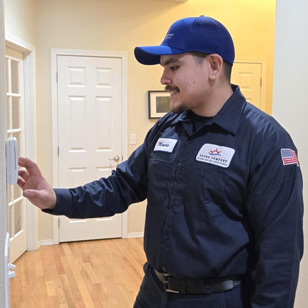 Sound Comfort Heating technician checking a thermostat in a Snohomish County home